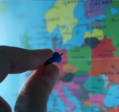 A hand pinning a map of Europe